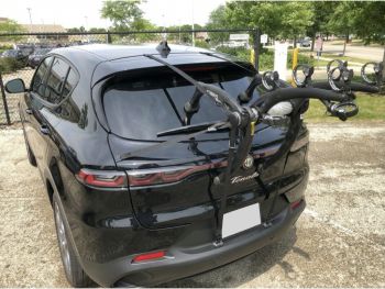 black Alfa Romeo Tonale with a bike rack fitted photographed close at the rear near a grass area focusing on the bike rack 