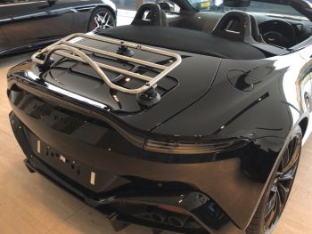black aston martin vantage volante convertible with a revo-rack pa luggage rack fitted in an aston martin showroom roof down