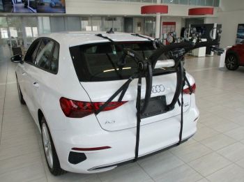 White Audi A3 Sportback TYP Y3  with a 3 bike rack fitted photographed close at the rear in an Audi showroom