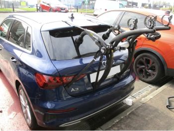 dark blue audi a3 S3 2024 TYP 8Y in with a bike rack fitted photographed close at the rear focusing on the bike rack in a car park next to an orange car