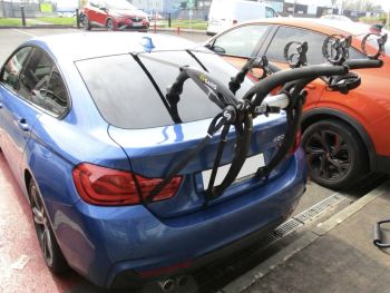 blue bmw 420d 4 series gran coupe in a car park with a bike rack fitted photographed close at the rear focusing on the bike rack