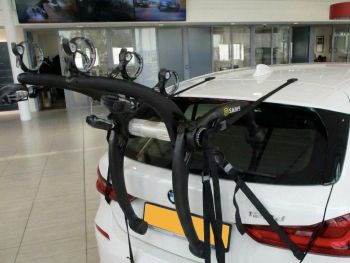 white bmw 1 series F20 F21 hatchback with a 3 bike rack fitted in a used car showroom