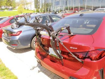 red bmw 2 series gran coupe F74 with a bike rack fitted photographed close at the rear outside a bmw dealership