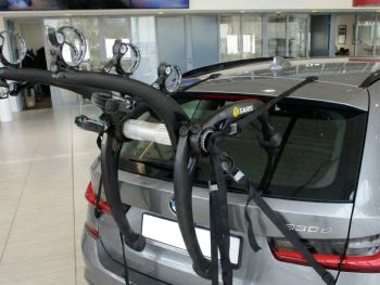 grey bmw g21 330d touring estate with a 3 bike rack fitted photographed close at the rear in a used car showroom