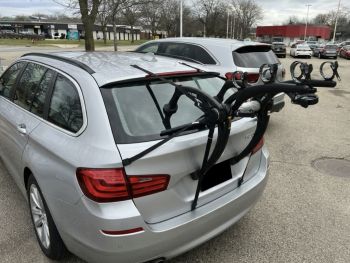 Silver bmw 5 series estate touring 530d in a car park with a bike rack fitted photogprahed close at the rear focusing on the rack