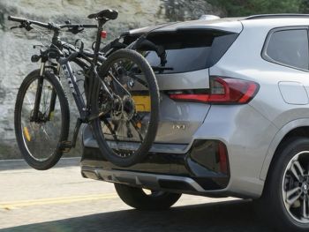 Silver Graphite BMW ix1 with a 2 bike rack fitted carrying a mountain bike photographed close at the rear 