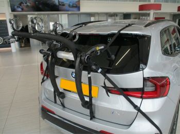 silver BMW ix1 U11 in a showroom with a Saris Bones EX3 bike rack fitted photographed close focusing on the bike rack