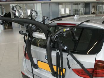 silver bmw x1 E84 with a 3 bike rack fitted to the tailgate photographed close at the rear in a showroom