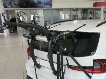 White bmw x1 u11 in a showroom with a 3 bike rack fitted to the tialgate photographed close at the rear 