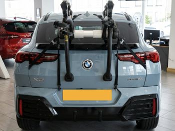 light blue bmw x2 u1§0 in a car showroom with a 3 bike rack fitted to the rear photographed close to focus on the bike rack
