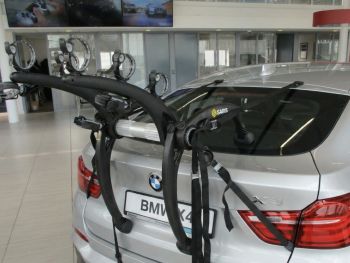 Silver bmw X4 in a bmw showroom with a 3 bike rack fitted to the rear photographed close