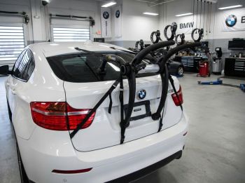 White bmw x6 with a 3 bike rack fitted p[photographed from the rear in the workshop of a bmw garage