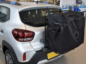 Silver Dacia Spring inside a Dacia Showroom with a hatch-bag roof box alternative fitted top the rear photographed close up