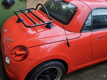 Daihatsu copen in red with a black revo-rack luggage rack fitted on a rainy day 