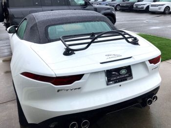 white Jaguar f type convertible in the rain with a black boot rack fitted  photographed outside a Jaguar dealership