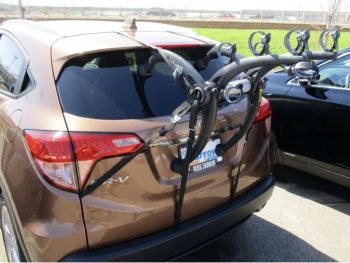 bronze honda hr-v hrv with a bike rack fitted to the tailgate photographed close at the rear focusing on the bike rack in a car park near a grassy area on a sunny day