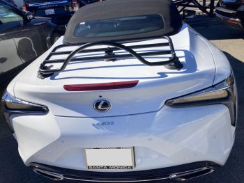 White Lexus LC 500 Convertible with a black luggage rack fitted photographed outside a lexus showroom on a sunny day