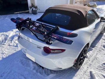 white mazda mx5 nd in the snow with a luggage rack and ski rack fitted carrying a set of skis