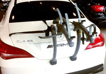 white mercedes cla 45 saloon with a bike rack fitted photographed from behind with a bike rack fitted in a mercedes showroom