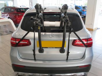 Silver Mercedes GLC with a 3bike rack fitted photographed close from the rear in a car showroom
