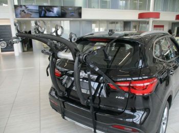 Black MG HS in an MG Showroom with a 3 bike rack fitted to the rear photographed close.