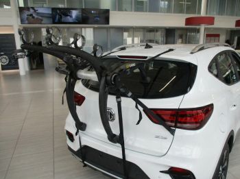 white MG ZS in an MG Showroom with a 3 bike rack attached photographed close from the rear 