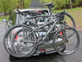 silver grey mini cooper with a 3 bike rack fitred carrying bikes photographed close at the rear in a car park