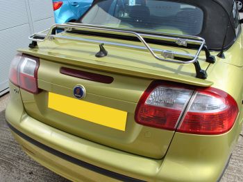 Green yellow metallic saab 93 cabriolet next to a garage door with a stainless steel luggage rack fitted 