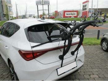 White seat leon parked on a garage forecourt photographed from the rear with a bike rack fitted to then tailgate photographed close focusing on the bike rack