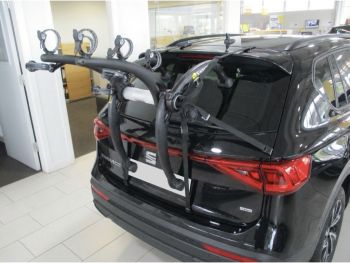 Black Seat Tarraco in a car showroom next to an office photographed close for the rear with a bike rack fitted to the tailgate with the photo focus on the bike rack