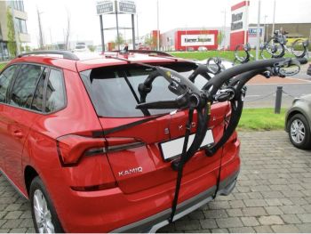Bright red skoda kamiq outside a garage with a bike rack fitted to the tailgate photogprahed close at the rear focusing on the bike rack