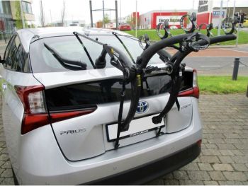 silver 2019 toyota prius xw50 with a bike rack fitted to the rear tailgate outside a car showroom photogprahed close focusing on the bike rack