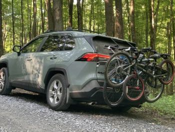 grey green toyota RAV 4  four on a gravel roads with a 3 bike rack fitted carrying 3 bikes 