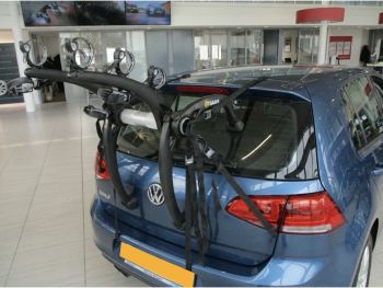 blue vw golf mk7 in a showroom with  a bike rack fitted for 3 bikes photographed close at the rear focusing on the bike rack