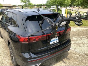 black volkswagen VW Tiguan 2024 2025 2026 model CT1 with a 3 bike rack fitted to the rear parked opposite a sports field photographed close art the rear 