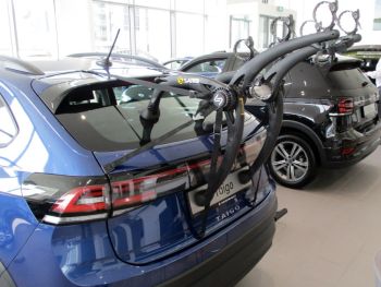 Blue Volkswagen VW Taigo in a VW showroom photographed close at the rear with a bike rack fitted to the tailgate with the photo focusing on the bike rack