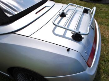 silver alfa romeo 916 spider with a luggage rack fitted to the boot in a field on a sunny day