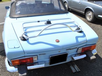 Classic light blue Fiat 124 Spider with a stainless steel luggage rack fitted on a sunny day
