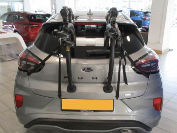 silver ford puma in a ford dealership with a 3 bike rack fitted to the tailgate photographed close at the rear 