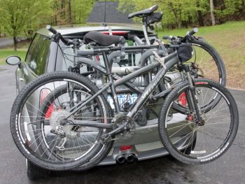 silver grey mini cooper with a 3 bike rack fitred carrying bikes photographed close at the rear in a car park