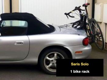 Silver mazda mx5 with a saris sol bike rack fitted on a driveway outside a house photographed from the side